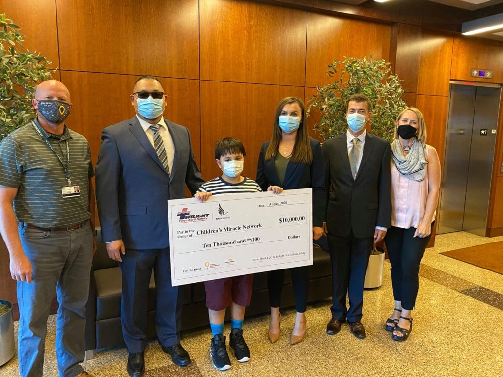 boy holding check with five well dressed individuals surrounding